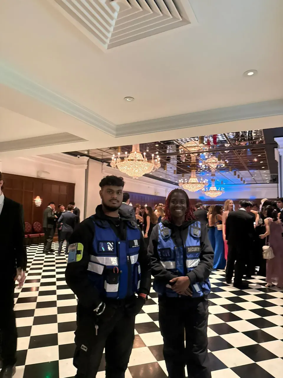 Two Zentinel officers at a black tie ball in a chandelier ballroom