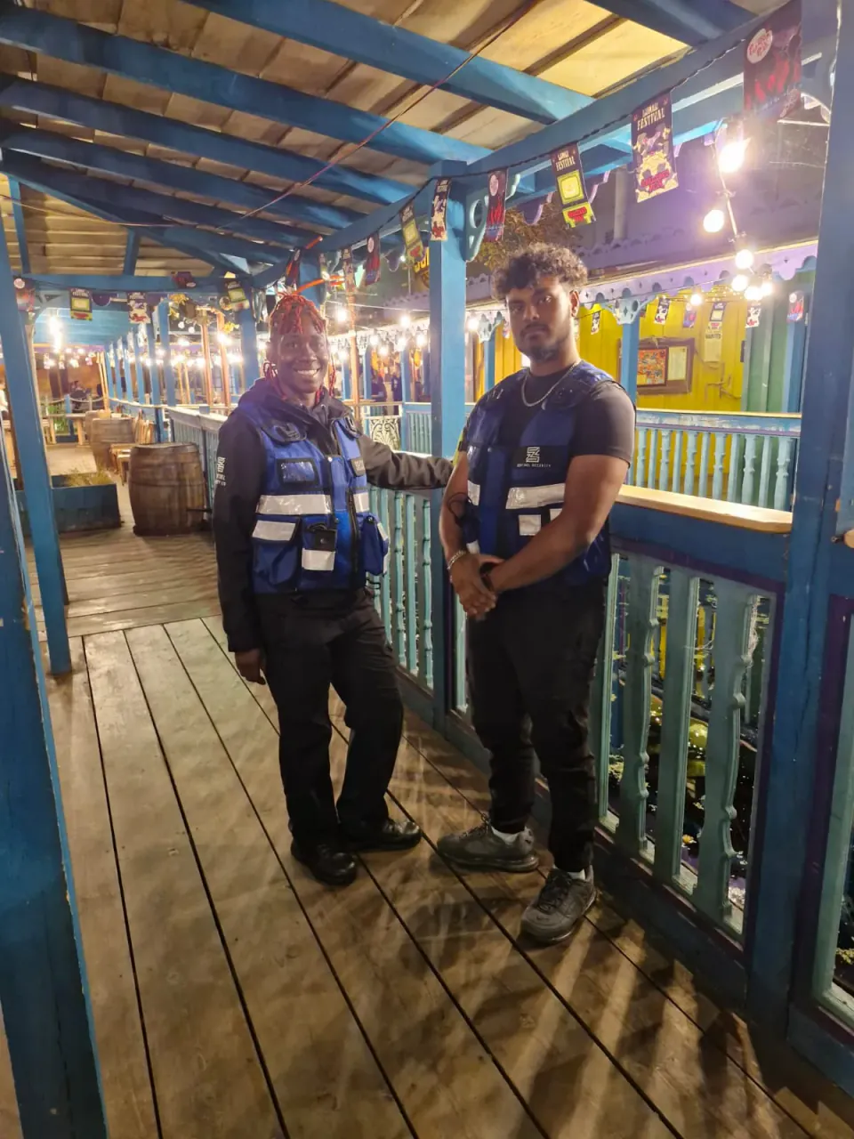 Two Zentinel officers on duty at a tiki bar venue walkway at night