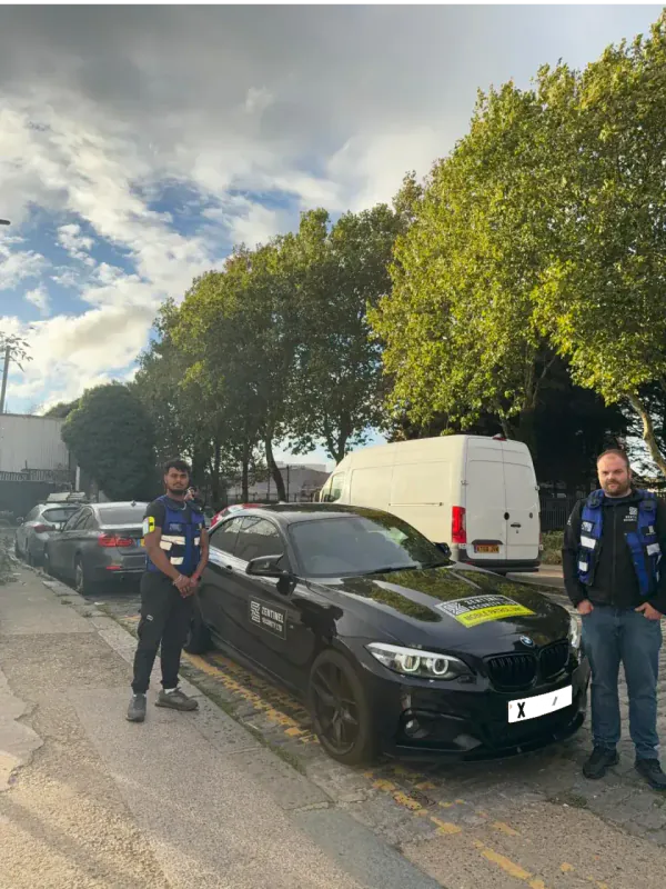 Two Zentinel officers beside a branded BMW patrol car in London